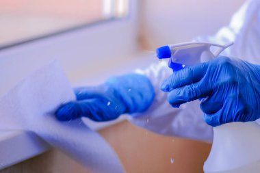 Koca bakımı ve temizlik konsepti mavi eldivenli mutlu genç adam evde yerleri temizlerken sprey ve toz bezi kullanıyor.