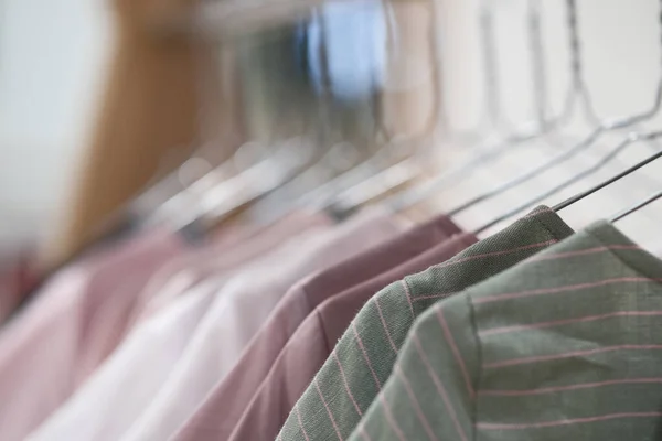 Textile and linen dresses hang on wooden hangers.