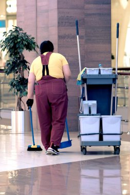 Temizlikçi çöpü süpürür. Alışveriş merkezinin ıslak temizliği için evrensel bir set. Modern bir temizlik şirketi, tekerlekli bir tramvayda temizlik seti, her amaç için mükemmel bir tasarım..
