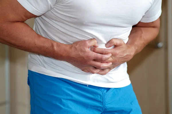 Manos de un hombre sosteniendo su estómago, sufriendo de dolor, diarrea, problemas digestivos —  Fotos de Stock