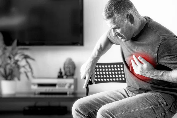 El hombre experimenta dolor en el pecho causado por un ataque al corazón. Enfermedad cardíaca en un anciano con antecedentes aislados en blanco y negro. El concepto de seguro médico para las personas mayores. —  Fotos de Stock