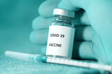 Bir doktor koruyucu mavi tıbbi eldivende bir ampul Sputnik V koronavirüs aşısı tutuyor.