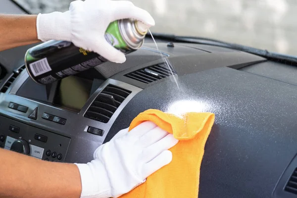 Egy műanyag tisztító és egy rongy a tisztító kezében. A kocsi belsejét takarítom. Takarító cég. Személygépjármű-belső gondozás. Stock Kép