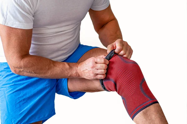 Muž upraví kompresní obvaz na kolenním kloubu. Sportovní zranění. — Stock fotografie