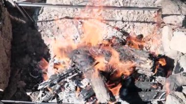 Yanan ağacın tepesinden büyük bir ateş altında kömürleri barbeküye hazırlarken.