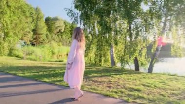 Güneş batarken gölde yürüyen gözlüklü genç sarışın kadın, bir yaz akşamı, 4K