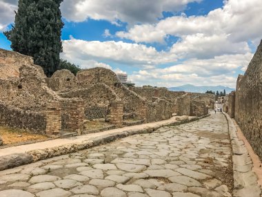Boş antik Roma şehri Pompeii bulutlu mavi gökyüzünün altında. Pompeii 'de terk edilmiş bir caddenin panoraması. Şehir kalıntıları, kaldırımlı yollar.
