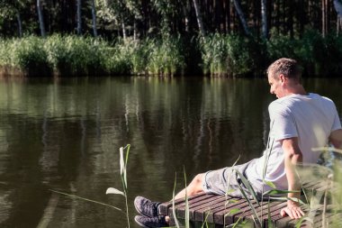 Ağaçlar ve yeşilliklerle çevrili güneşli bir yaz gününün tadını çıkaran mutlu ve rahat bir adam. Akıl sağlığı, yeniden başlat
