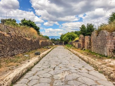 Boş antik Roma şehri Pompeii bulutlu mavi gökyüzünün altında. Pompeii 'de terk edilmiş bir caddenin panoraması. Şehir kalıntıları, kaldırımlı yollar.