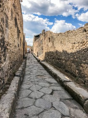 Boş antik Roma şehri Pompeii bulutlu mavi gökyüzünün altında. Pompeii 'de terk edilmiş bir caddenin panoraması. Şehir kalıntıları, kaldırımlı yollar.