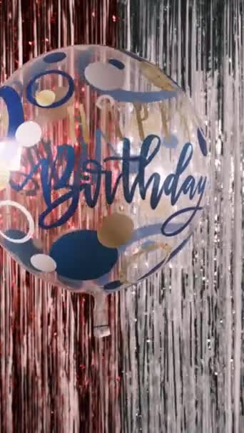 誕生日おめでとう。碑文と透明なヘリウム気球の垂直ショット幸せな誕生日光沢のあるお祝いのティンセルの背景に, 4k — ストック動画