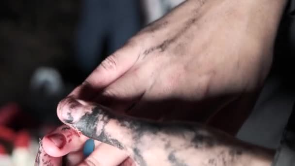 Close-up van handen gekleurd met verf. Kunstenaar probeert verf van zijn handen te wassen in het donker — Stockvideo