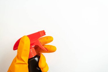 Beyaz arka planda elinde turuncu eldivenle siyah temizleme spreyi. Temizlik, temizlik ve ev kimyasalları kavramı