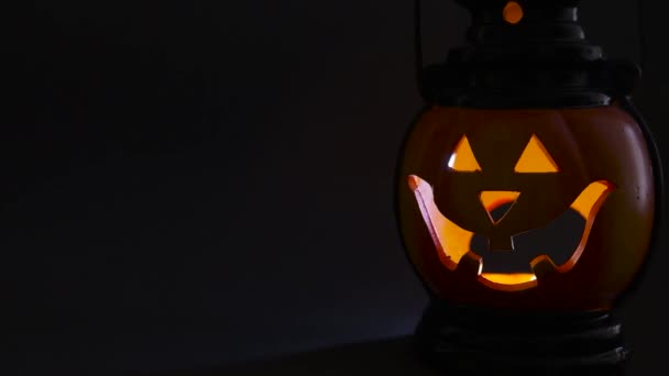 Halloween, horror i koncepcja mistycyzmu. Migocząca świecąca pomarańczowa dynia z wyrzeźbioną twarzą w ciemności, dozwolone tło, miejsce na tekst, przestrzeń do kopiowania — Wideo stockowe
