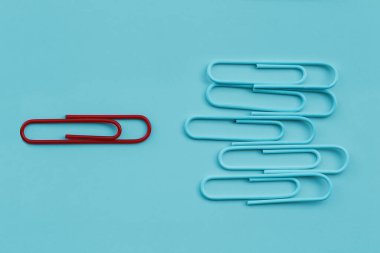 Mavi pastel arka planda bir grup ataç ve zıt yönde bir birey olarak iş minimal kavramı. İş liderliği fikri, farklı düşünüyor..