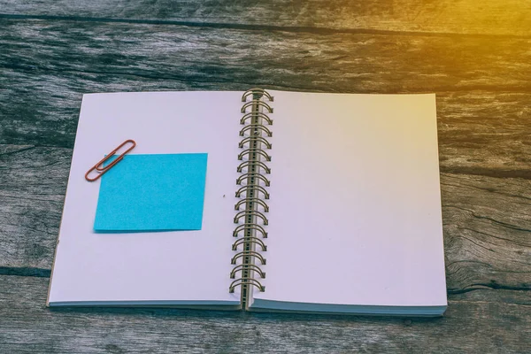 木製のバックグラウンドオフィスの机の上に空白のノートブルーの紙シート テキストメッセージを追加します 記憶の日のノートの物語毎日 ホームワークスペースのコンセプト — ストック写真