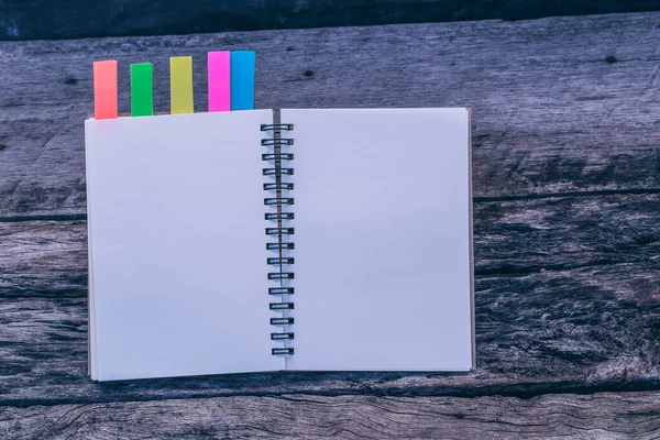 A blank diary or note pad with color tab on old wooden table, Vintage picture tone.The idea about the work that has been saved to achieve the goal. copy space.