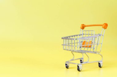 Sarı arka planda turuncu boş metal sepet yakın çekim ticaret konsepti