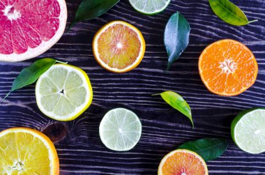 Limonlu limon portakalı greyfurt ve koyu ahşap arka planda yeşil yapraklar.