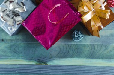 Parlak renkli hediye kutuları, fiyonklu çantalar ve dekoratif elementler ahşap arka plan kopi uzay üst görünümü üzerinde