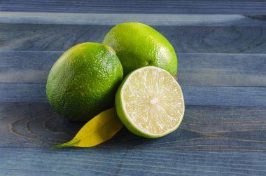 Taze yeşil limon ve ahşap arka planda yarım limon. Yakın plan.