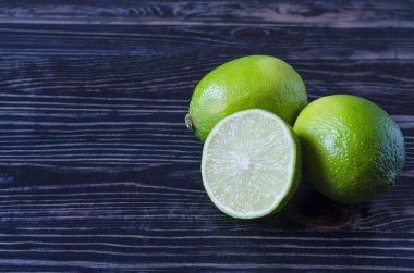 Taze yeşil limon ve yarım limon kopi uzayının ahşap arka planında