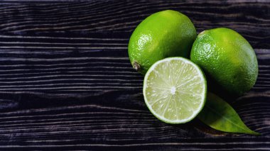 Taze yeşil limon ve yarım limon kopi uzayının ahşap arka planında