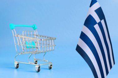 Renkli arka plan tüketici sepeti kavramında boş metal alışveriş sepeti ve Yunan bayrağı