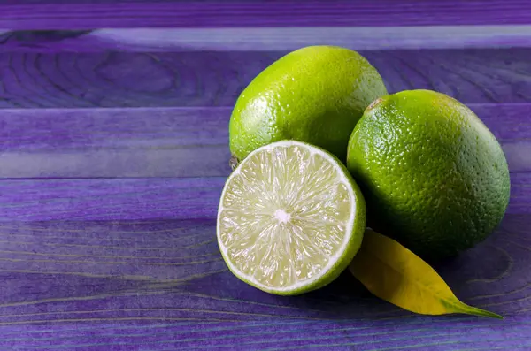 Limes Vertes Fraîches Demi Citron Vert Sur Fond Bois Violet — Photo