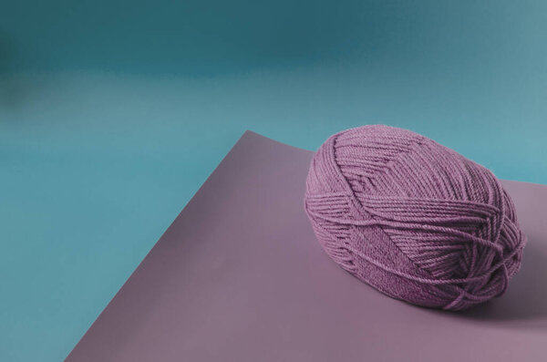 a ball of lilac yarn on a colored background close-up. knitting in self-isolation