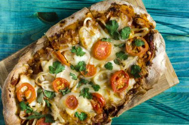 Ahşap arka plan manzaralı domatesli ve otlu Pinsa. Pinsa ev yemeği. Pizza hamur işleri.