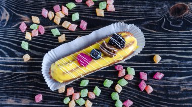 Yapay böğürtlenlerle süslenmiş krem şantili ve koyu ahşap arka plan manzaralı renkli pastalar. Kopi uzay keki