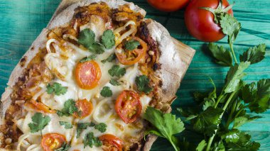 Domatesli Pinsa ve ahşap arka plan manzaralı taze otlar. Pinsa ev yapımı, yakın çekim..