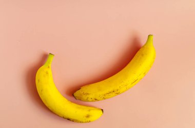 Renkli arka planda iki parlak sarı muz. Büyük sarı muzlar kopi uzayının üst görüntüsü