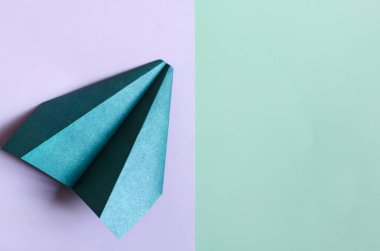 İki tonluk mor-yeşil arka planda yeşil kavramlı kağıt uçak. Origami parlak yeşil kağıt uçak
