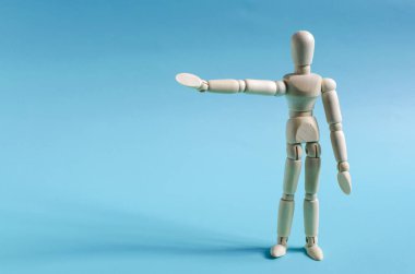 Elleriyle boş bir yeri gösteren tahta bir adam figürü. Renkli arka plan kopi uzayında tahta bir adam figürü.