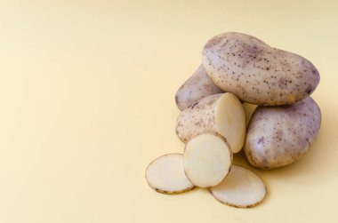 Renkli bir arka planda patates ve yarım patates. Kopi uzayının renkli arka planında patatesler