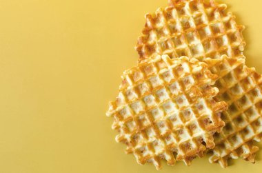 Sarı arka planda çıtır waffle 'lar. Renkli arka plan kopi alanı üzerinde ev yapımı kekler çıtır çıtır waffle.