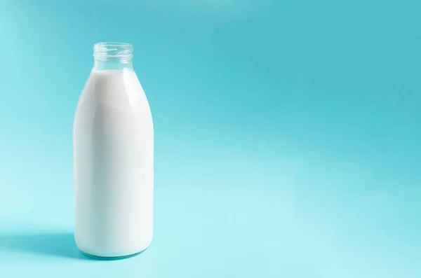 A glass bottle with milk on a blue background. A liter of milk in a glass bottle on a colored background a place for text