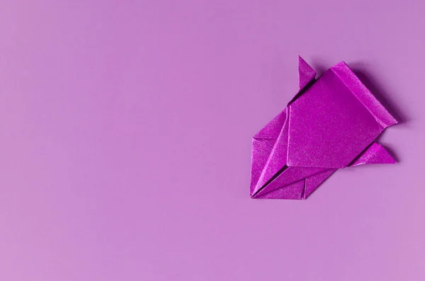 A lilac-colored paper car on a lilac background of the kopi space. Origami bright purple paper car