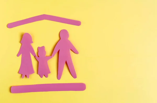 Figures of a family of two adults and a child and symbols symbolizing protection on a yellow background. The concept of family protection.
