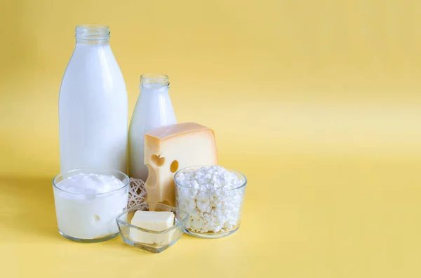 A set of milk products on a yellow background of kopi space. Milk, kefir, sour cream, cheese, butter and cottage cheese on a light background close-up