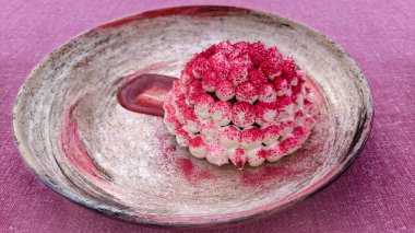 Un, yağ, yumurta, şeker ve diğer malzemelerden oluşan pembe bir piramit şeklinde tatlı bir yemek. Yuvarlak bir tabakta pembe pudrayla kaplı beyaz bir top kek var. Seçici odak.