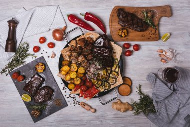 Süslü ve patatesli yuvarlak tabakta çeşitli et ve kebaplar.