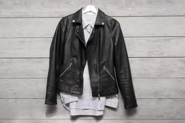 Giysi mağazasının arka planında siyah deri ceket ve gömlek var..