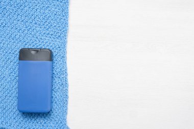 Duş jeli ve örgü eşarp beyaz ahşap masa arkasında.