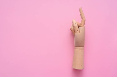 Tahta el, pembe arkaplanda işaret parmağıyla fotokopi alanı ile beliriyor..
