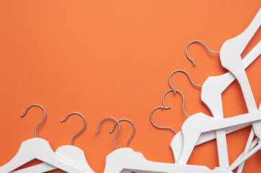 Beyaz elbise askısı turuncu düz arka planda fotokopi alanı ile yatıyordu.