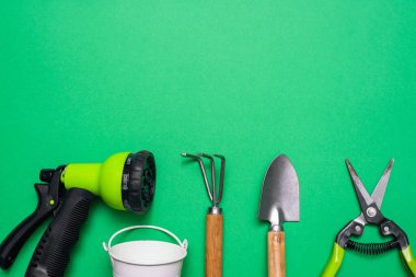 Yeşil arkaplanda kopyalama alanı olan bahçe araçları. Tırmık, kürek, secateurs ve küçük su kovası.