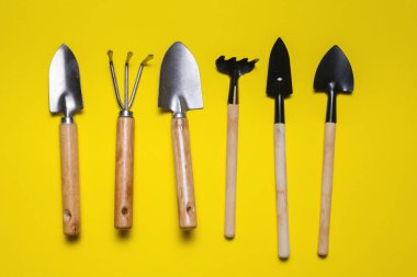 Sarı düz zemin üzerinde bahçe araçları yatıyordu. Bahçıvanlık.